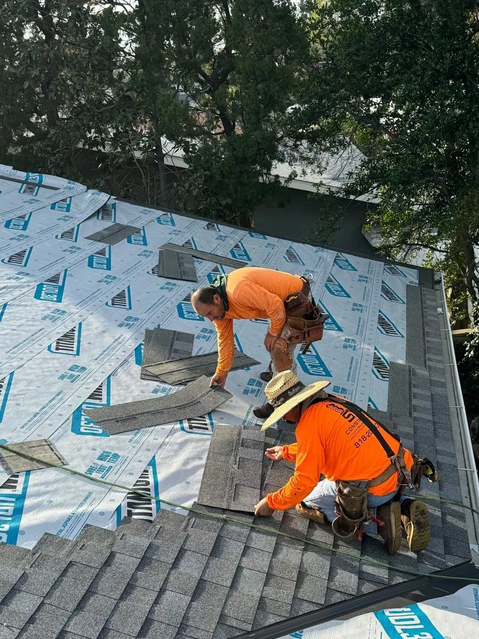 Crew installing asphalt shingles over new underlayment